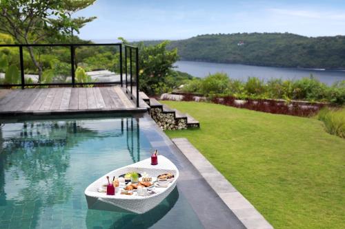 a boat with food on it sitting next to a swimming pool at MAUA Nusa Penida Bali in Nusa Penida