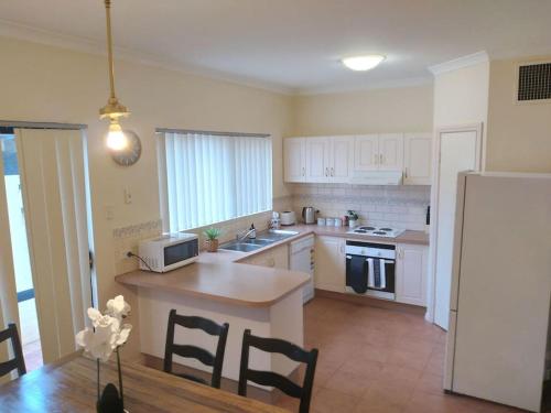 a kitchen with white appliances and a table and chairs at Across the road from the best Pub in Kalgoorlie!!! in Kalgoorlie