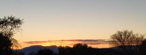 a sunset with trees and mountains in the background at Amberly House Rotorua in Rotorua