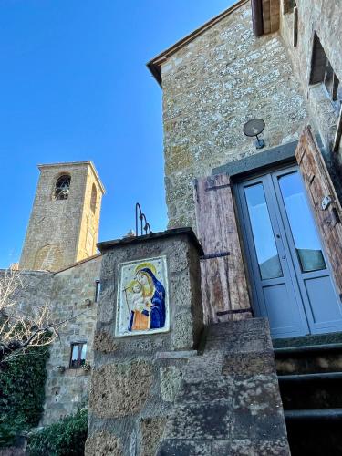 a painting on the side of a building with a clock tower at Flaminivs - Timeless Elegance in Civita di Bagnoregio in Bagnoregio