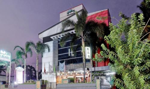 um edifício com palmeiras em frente em Treebo Trend Symphony Hotels And Resorts Angamally em Kizhake Chālakudi