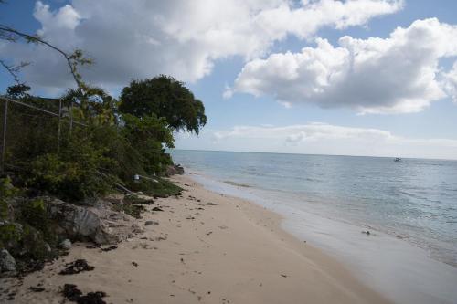 a sandy beach with the ocean on a cloudy day at Bianca Bay 3 Bedroom West Coast Beach Front Villa in Saint James