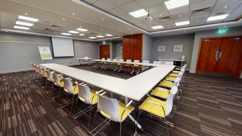 a conference room with a long table and chairs at Holiday Inn Milton Keynes Central by IHG in Milton Keynes