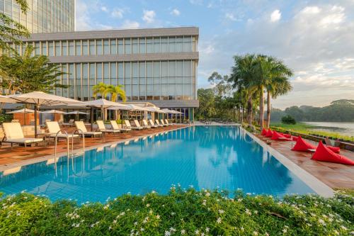 a large pool with chairs and umbrellas in front of a building at LOTTE Hotel Yangon in Yangon