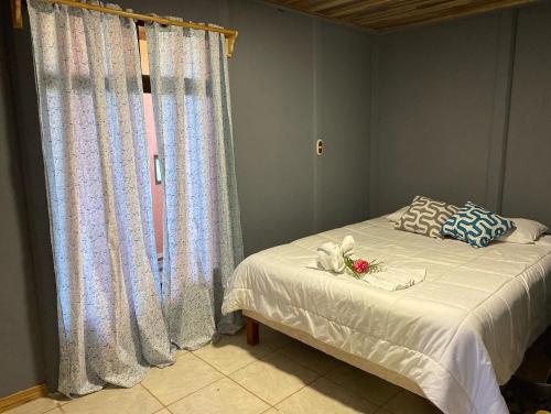 a bedroom with a bed with white sheets and a window at MâpleTico Casita in Monteverde Costa Rica