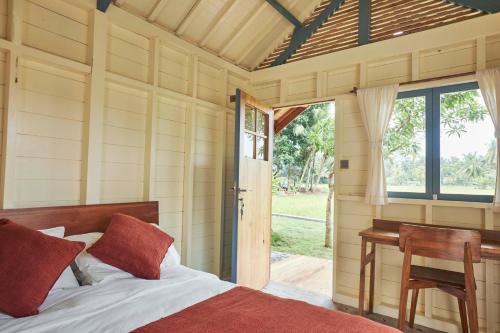 een slaapkamer met een bed, een bureau en een raam bij House of Sawah in Batukaras