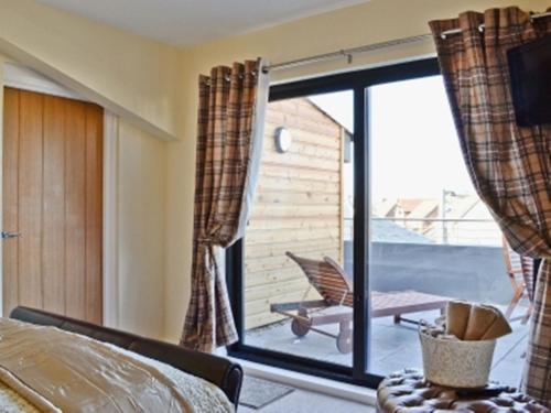 a bedroom with a bed and a sliding glass door at The Penthouse- The Kingsley Collection in Troon