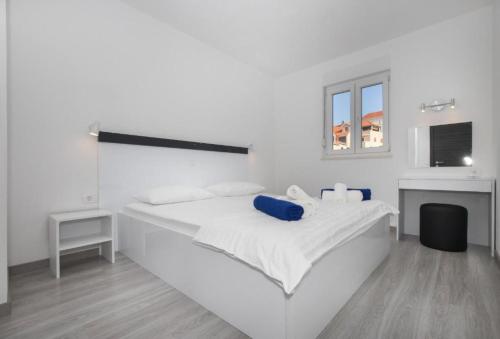 a white bedroom with a white bed and a window at Apartments Jakov - modern and cosy with pool in Postira