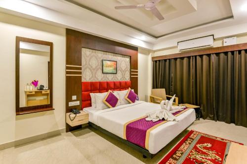 1 dormitorio con 1 cama grande y espejo en Mount Amara Hotel & Spa, Siliguri en Siliguri