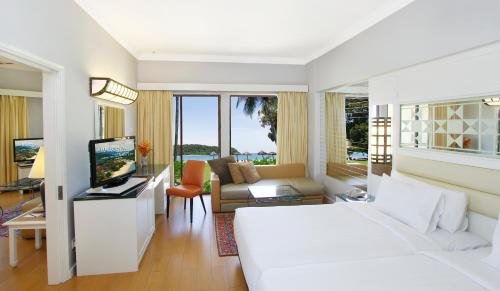 Holiday Villa Resort & Beachclub Langkawi في بانتايْ سينانج: غرفة نوم بسرير ابيض وغرفة معيشة