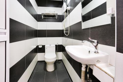 a black and white bathroom with a toilet and a sink at Super OYO 89495 Rich Hotel in Johor Bahru
