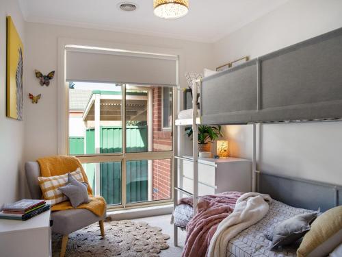 a bedroom with a bed and a chair and a window at Wayfarer Cottage in Daylesford