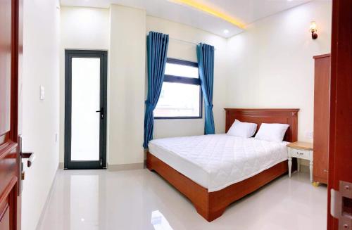 a bedroom with a bed and a window with blue curtains at Tiến Đạt Apartment in Nha Trang