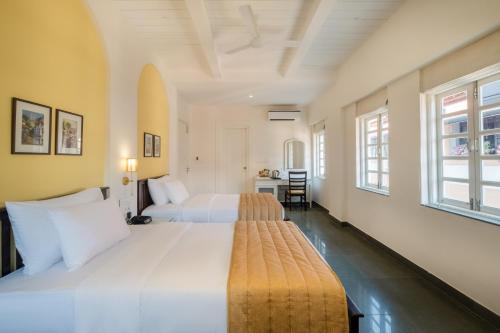 two beds in a large room with two windows at O Pierre in Panaji