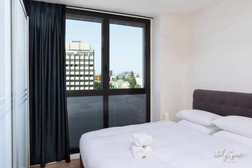 a bedroom with a white bed and a large window at Huge 3BR Penthouse by HolyGuest in Tel Aviv