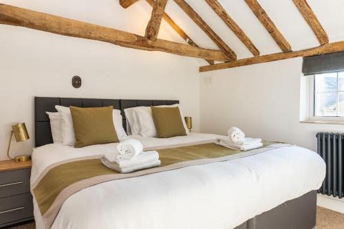 una camera da letto con un grande letto bianco con asciugamani di Stunning 4 Bedroom Cottage-Sleeps 8-Free Parking a Gloucester