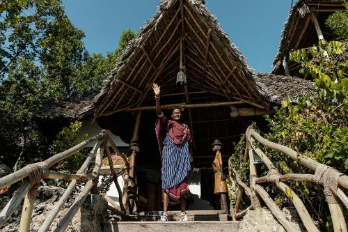 a woman standing on the steps of a house at The Island - Pongwe Lodge in Pongwe