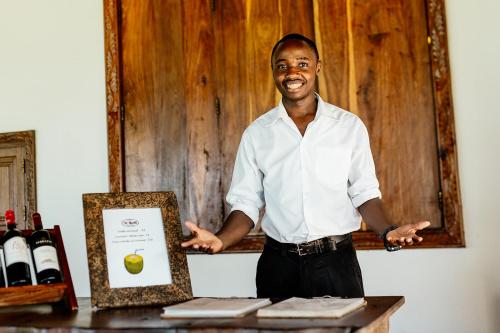 a man standing next to a table with a box of wine at The Island - Pongwe Lodge in Pongwe