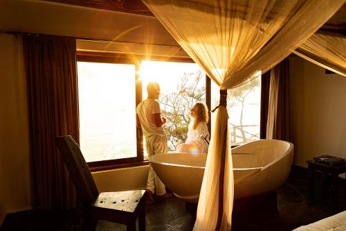 a man and woman standing in a bathroom looking out the window at The Island - Pongwe Lodge in Pongwe
