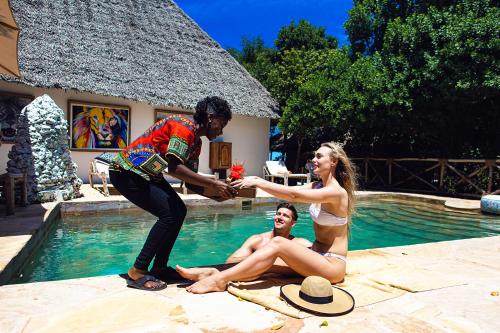 a man and a woman are sitting in a swimming pool at The Island - Pongwe Lodge in Pongwe