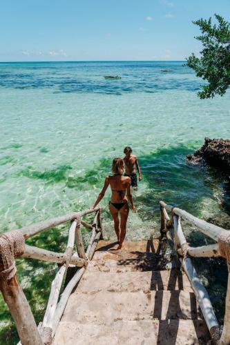 a couple of people walking into the ocean at The Island - Pongwe Lodge in Pongwe