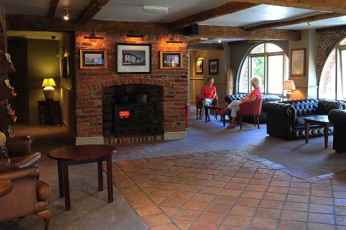 a living room with a fireplace and people sitting in chairs at Red Lion Hotel by Greene King Inns in Fareham