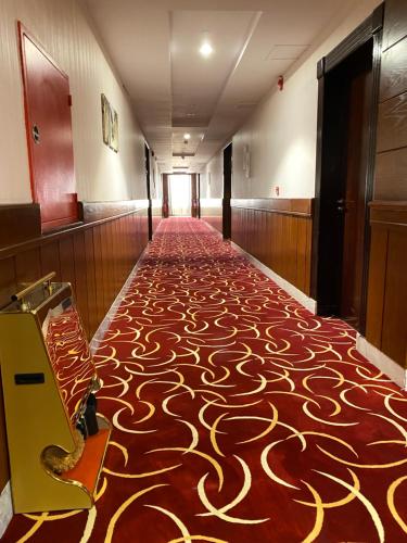 um corredor com um tapete estampado vermelho e dourado em Biz Hotel Apartments em Tabuk