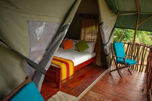 um quarto com uma cama e uma cadeira numa tenda em Camp Leopard - Yala Safari Glamping em Yala