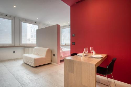 Apartment Passarella 4 في ميلانو: غرفة بجدار احمر وطاولة وكراسي