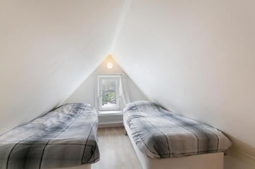 2 Betten in einem Dachzimmer mit Fenster in der Unterkunft Hello Zeeland - Vakantiehuis Beatrixstraat 27A in Domburg