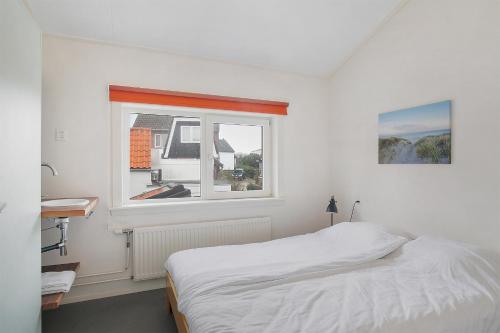a white bedroom with a bed and a window at Hello Zeeland - Appartement Beatrixstraat 27 in Domburg