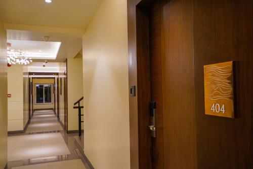 a hallway with a door with a sign on it at Hotel El Magnifico in Surat