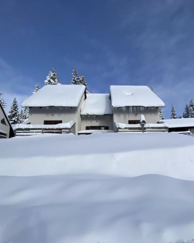 uma casa coberta de neve com árvores ao fundo em Apartma Idila em Zrece