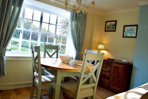 a dining room table with four chairs and a window at Charming Cottage, Great Rissington, Cotswolds in Great Rissington