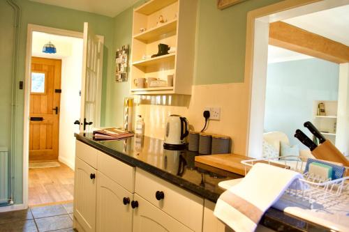 - une cuisine avec des murs verts et un comptoir dans l'établissement Charming Cottage, Great Rissington, Cotswolds, à Great Rissington