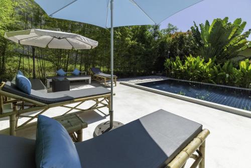 a patio with chairs and an umbrella and a pool at Moon Cottage in Choeng Mon Beach
