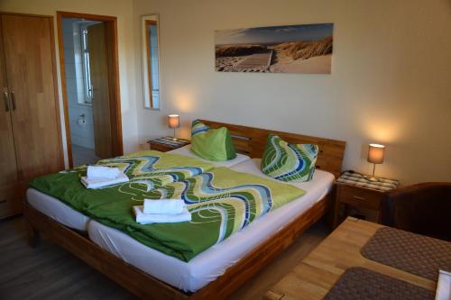 a bedroom with a bed with green sheets and pillows at Hotel Haus am Meer in Büsum