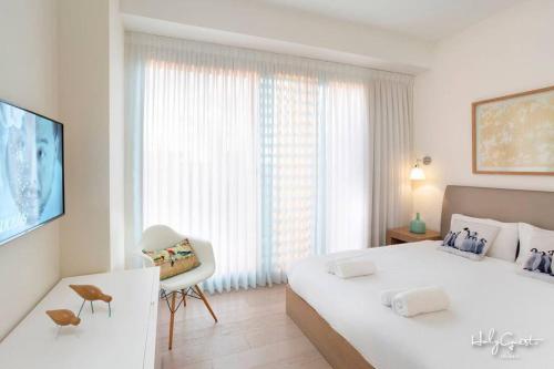 een witte slaapkamer met een groot bed en een raam bij Chic 1BR in White City by HolyGuest in Tel Aviv