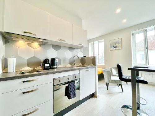 uma cozinha com armários brancos e uma sala de jantar em COLMAR - Appartements Deluxe - Lumineux - Stationnement Gratuit et Facile dans la rue em Colmar