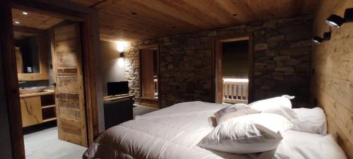 - une chambre avec un lit dans une pièce dotée d'un mur en pierre dans l'établissement Esprit de la Meije - luxury Chalet overlooking the Meije, à La Grave