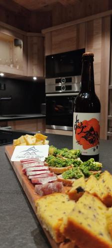 - une bouteille de bière assise à côté d'une table avec une pizza dans l'établissement Esprit de la Meije - luxury Chalet overlooking the Meije, à La Grave