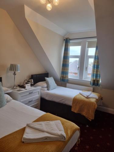 a bedroom with two beds and a window at St Leonards Guest House in Largs