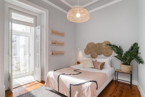 um quarto branco com uma cama e um vaso de plantas em Casa Boma Lisboa - Elegant and Charming Apartment - Alcantara V em Lisboa