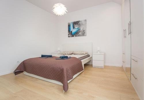 a white bedroom with a bed and a wooden floor at Urban Jungle Apartment in the city center in Białystok