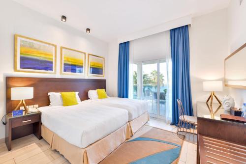 a bedroom with a large bed with blue curtains at Radisson Blu Resort, Fujairah in Dibba