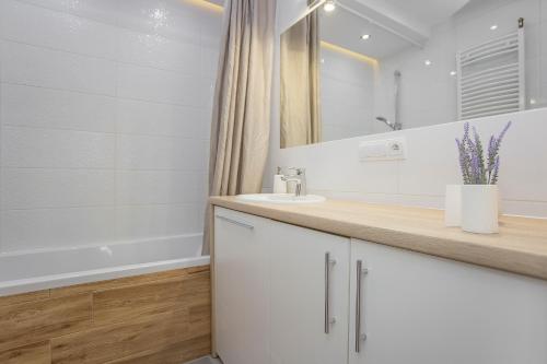 a white bathroom with a sink and a mirror at Urban Jungle Apartment in the city center in Białystok