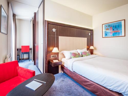 アヌシーにあるホテル ドゥ ボンリューのベッドと赤い椅子が備わるホテルルームです。