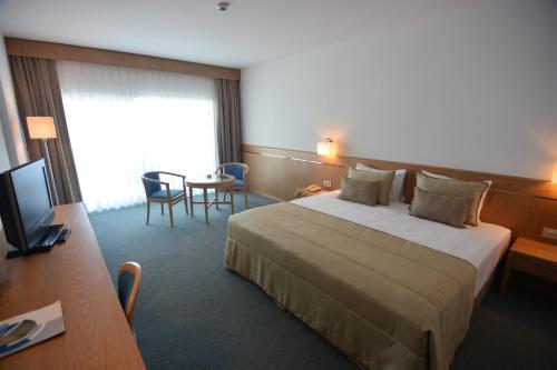 a hotel room with a large bed and a table at Grand Hotel Ontur Cesme in Cesme