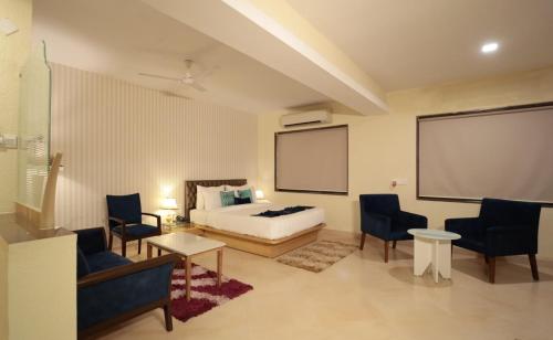 a hotel room with a bed and a table and chairs at Meritas Seawind Beach Resort, Shrivardhan in Srīvardhan