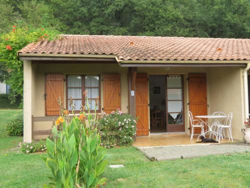 una pequeña casa con una mesa y sillas en un patio en bungalows les thuyas, en Eugénie-les-Bains